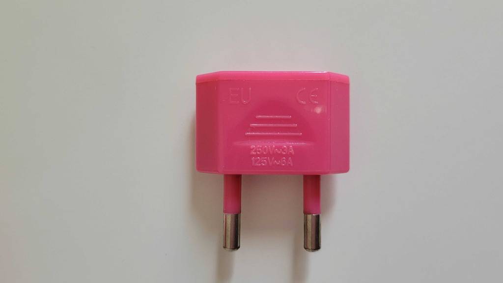getestet: Stecker eines Steckdosenadapters auf einer weißen Fläche liegend.