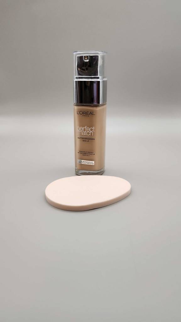 Die getestete L’Oréal-Foundation steht hinter einem Make-up-Pad.