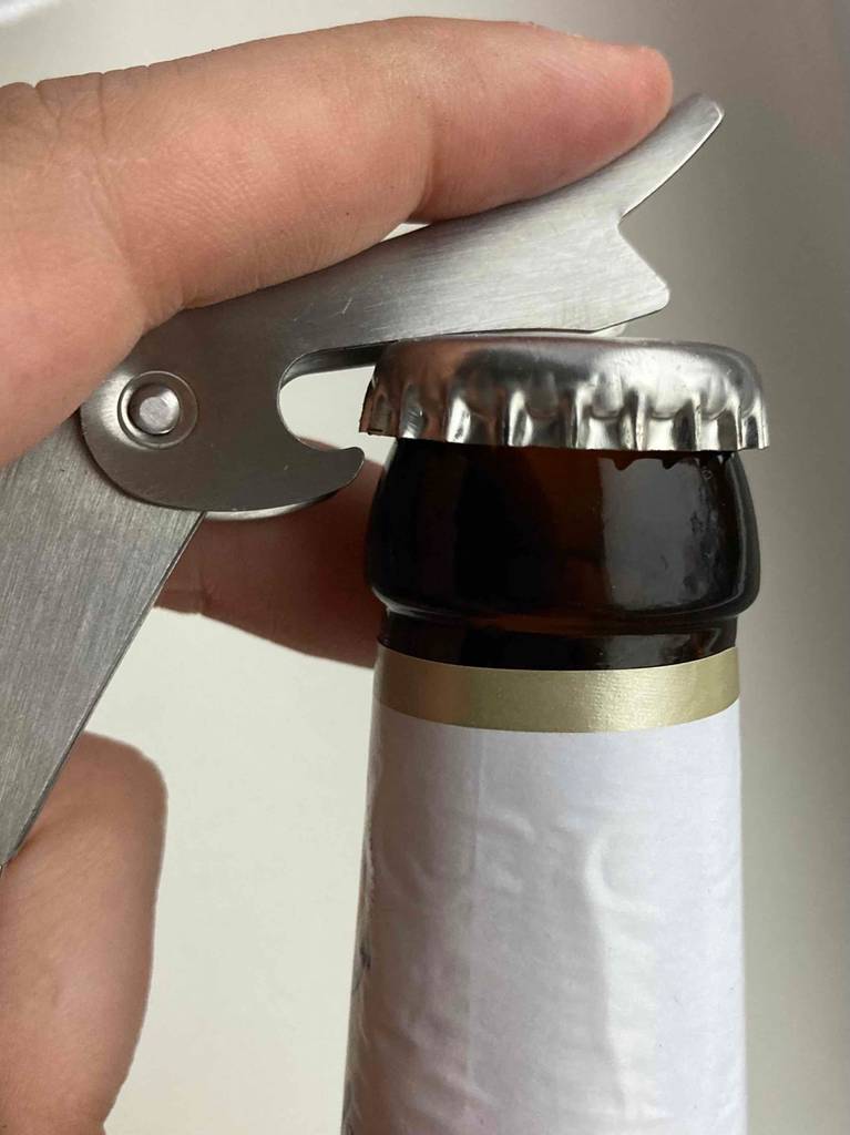 Im Test: Eine Hand öffnet eine Kronkorkenflasche mit einem Kellnermesser.