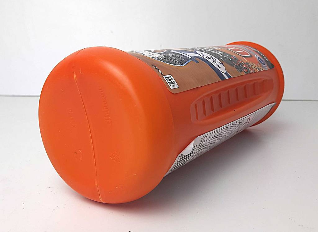 Nahaufnahme der liegenden orangefarbenen Kunststoffflasche einer Rohrreinigung im Test.