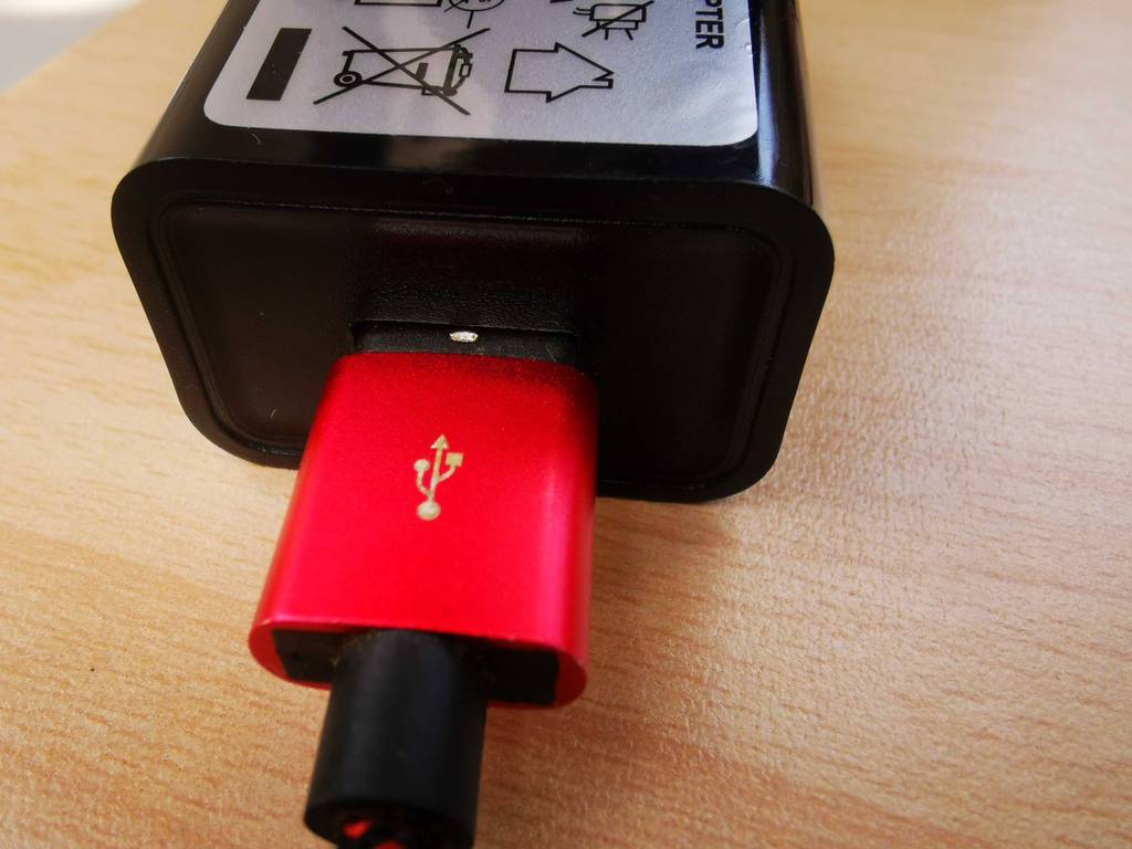 Ein rotes USB-Kabel steckt in dem getesteten USB-Ladegerät.