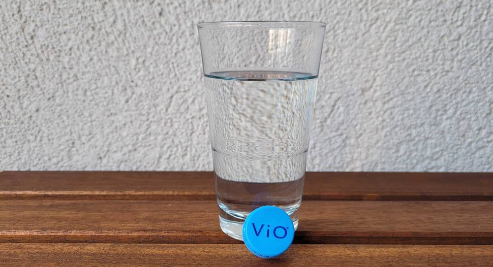 Stilles-Mineralwasser im Test: ein Glas Wasser mit einer Verschlusskappe eines Mineralwassers davor.