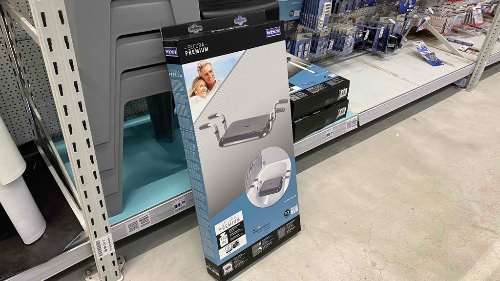 Im Test: Ein verpackter Badewannensitz von links seitlich vor einem Regal.