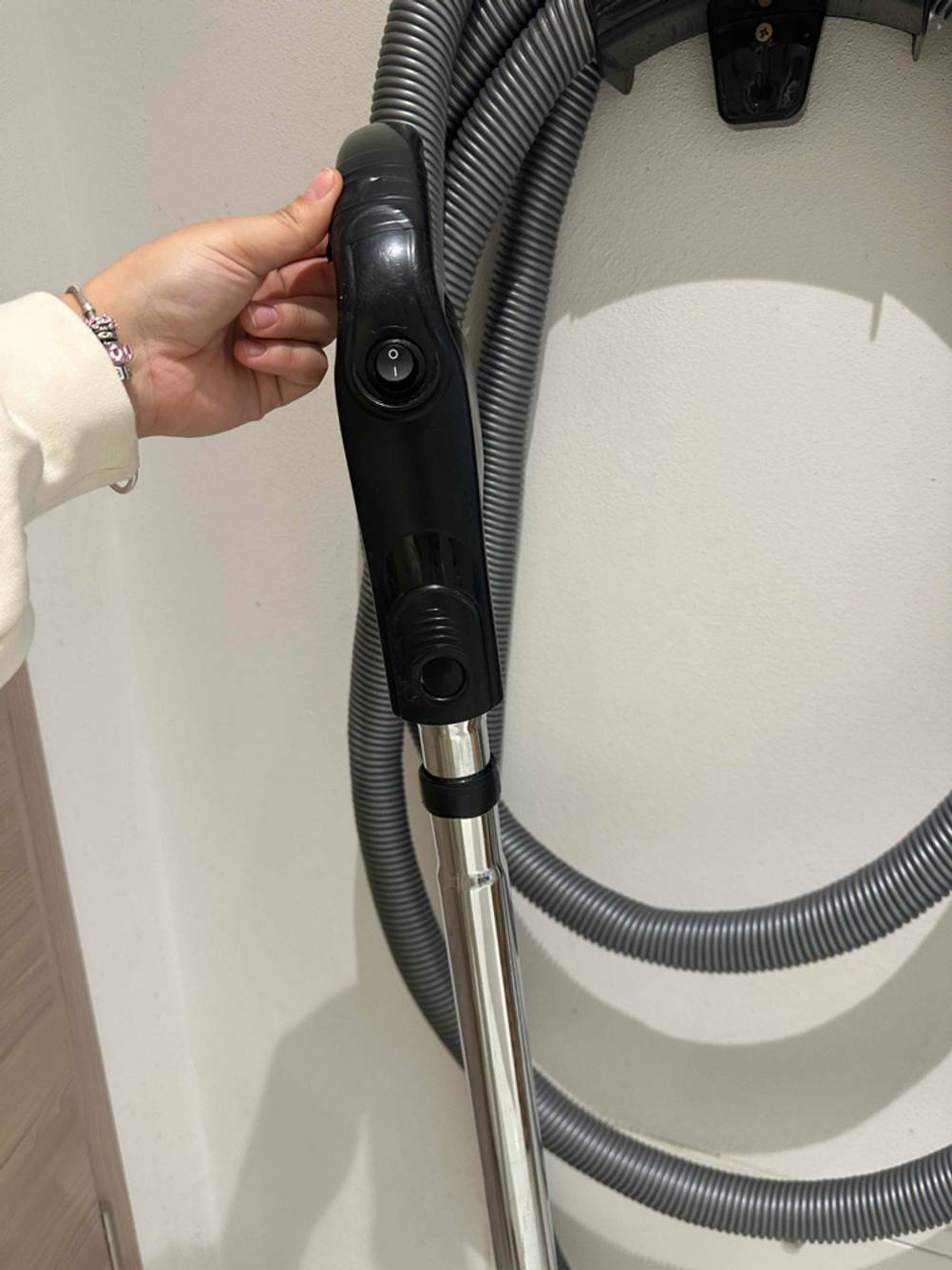 Griff eines getesteten Zentralstaubsauger mit Ein-Ausschalter wird in der Hand gehalten.