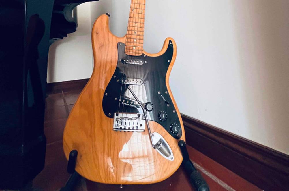 Auf einem Ständer steht eine getestete E-Gitarre vor einer hellen Wand.