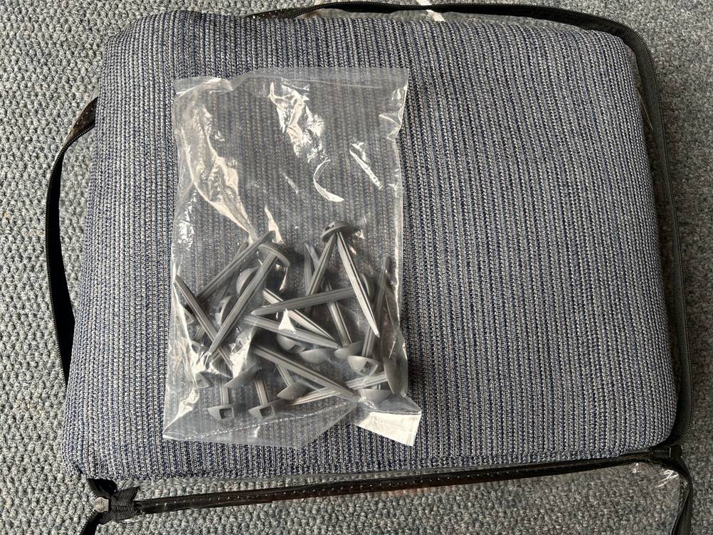 Im Test: Auf einem Zeltteppich liegen Zeltnägel in einer Plastiktüte.