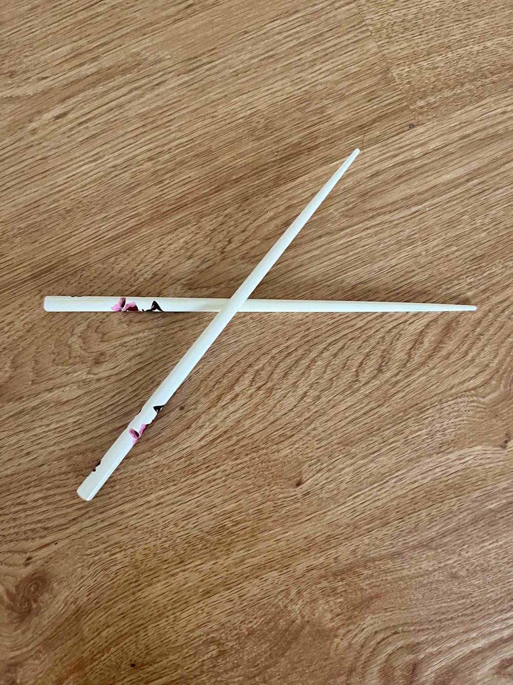 Essstäbchen im Test: zwei Essstäbchen liegen übereinander auf einer Holzfläche.