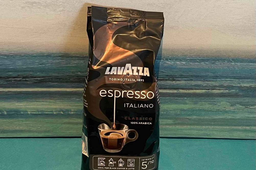 Im Test: Eine Packung Lavazza-Kaffeebohnen lehnt an einer blau-gestreiften Wand.
