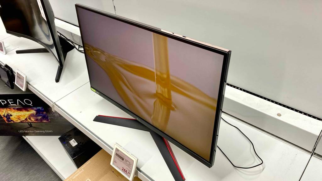 Gaming-Monitor im Test: ein Gaming-Monitor im eingeschalteten Zustand stehend in einem Regal mit Preisschild darunter ersichtlich.