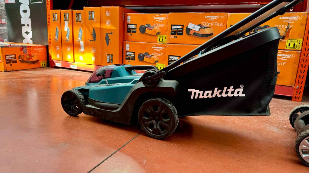 Der getestete Makita-Akku-Rasenmäher vor einem Regal.