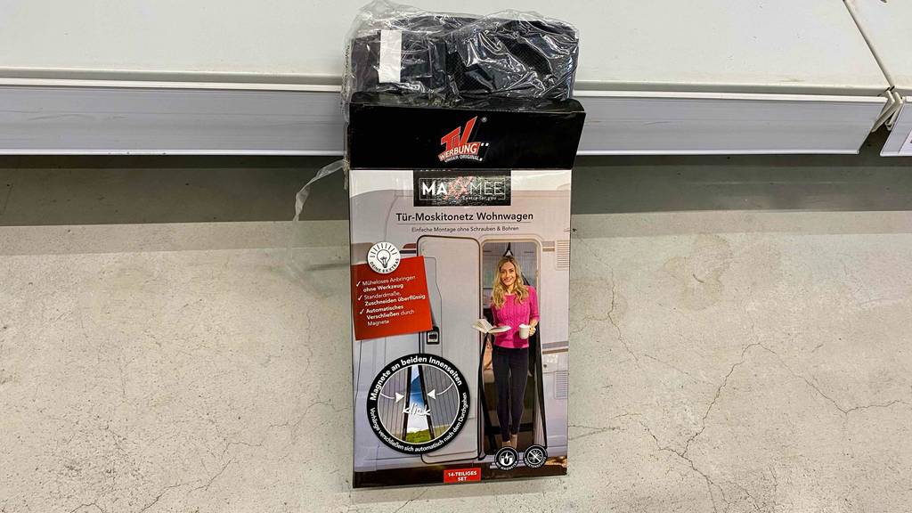 Die Verpackung eines Moskitonetzes mit herausschauendem Mosiktonetz ist an ein Regal angelehnt.