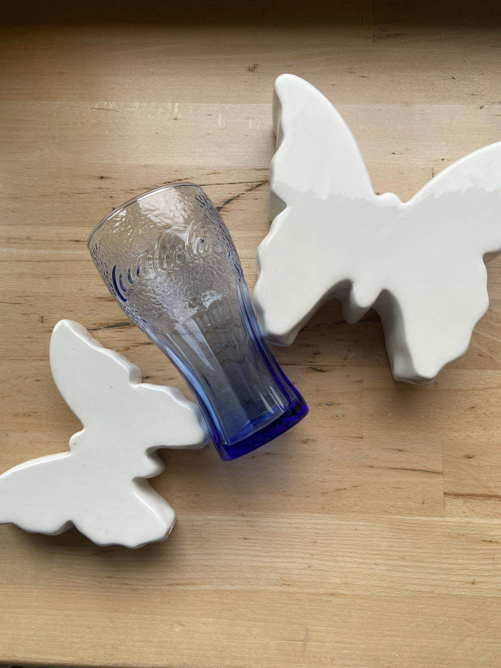 Ein blaues getestetes McDonald's-Glas liegt neben Dekoschmetterlingen.
