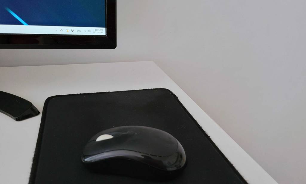 Getestete schwarze kabellose Maus auf einem schwarzen Mousepad.