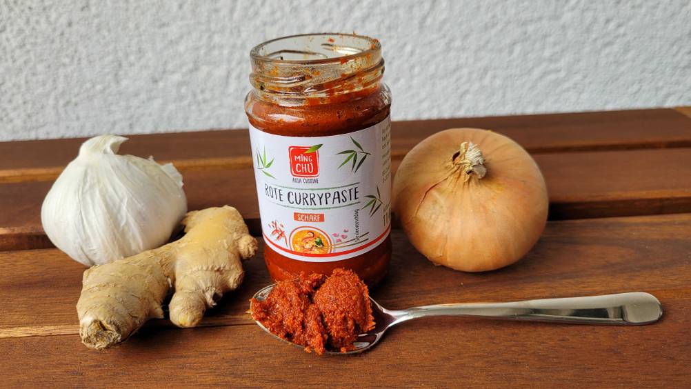 Currypaste auf einem Löffel mit verschiedenen Zutaten.