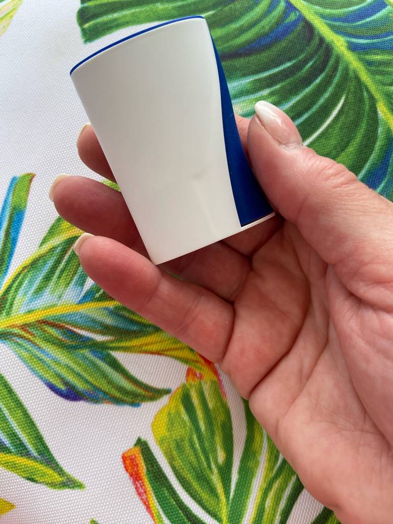 Eine Hand hält einen getesteten Süßstoffspender vor einem Stoff mit Palmenmuster.
