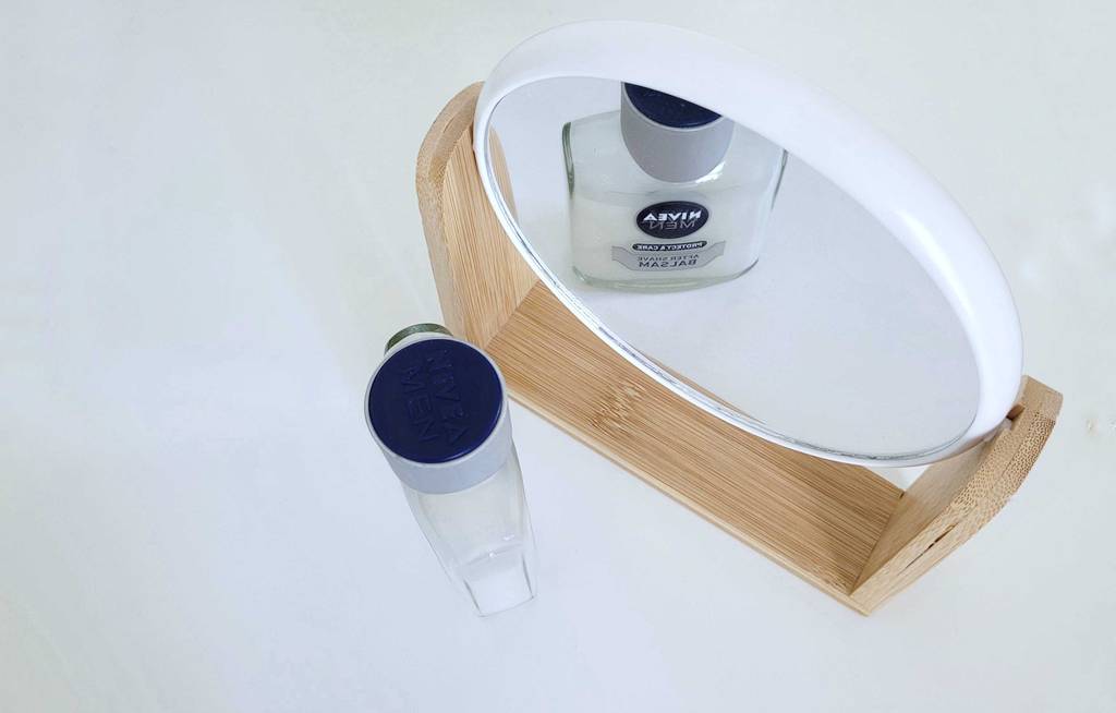 After-Shave-Balsam-Test: After-Shave neben Kosmetikspiegel stehend von oben.