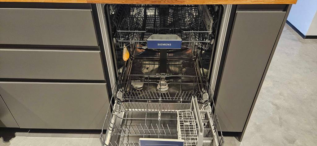 Ein getesteter vollintegrierbarer Geschirrspüler in einem Küchenunterbau mit geöffneter Türe.