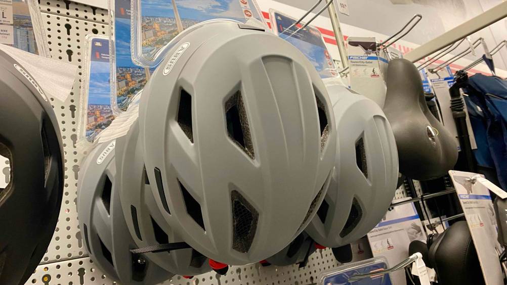 Abus-Fahrradhelm im Test: mehrere graue Abus-Fahrradhelme hängend in einem Regal.