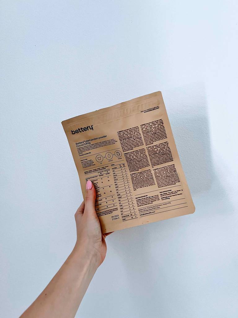Eine Hand hält die Rückseite des getesteten Erbsenproteins vor eine helle Wand.