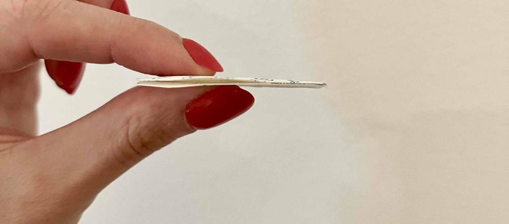 Blasenpflaster getestet: ein Blasenpflaster wird zwischen den Fingern vor eine weiße Wand gehalten.