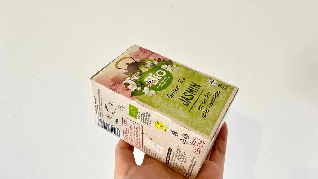 Eine Hand hält eine Verpackung von getestetem Jasmintee.