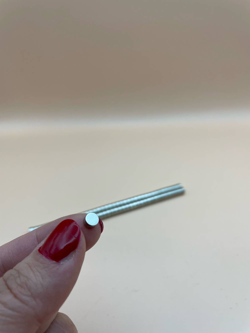 Ein kleiner Kühlschrankmagnet der getestet wurde wird an den Fingern in die Kamera gehalten.