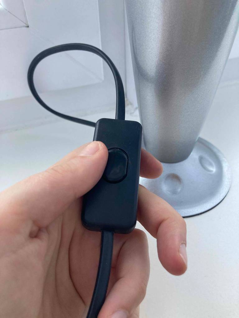 Eine Hand hält den Anschalter einer Lavalampe im Test.