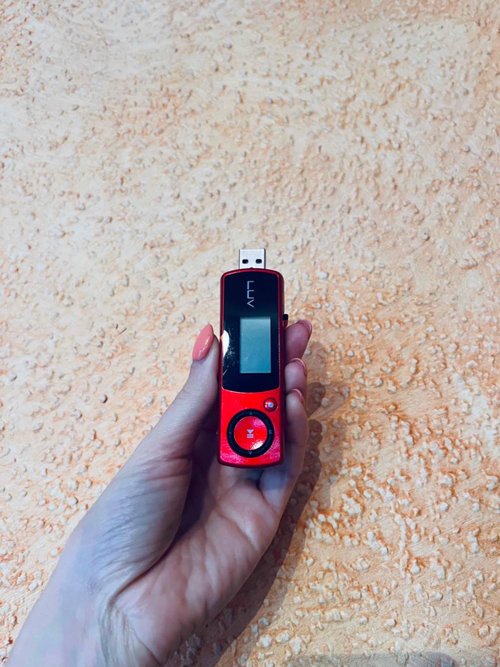 MP3-Player getestet: Eine Hand hält einen MP3-Player vor eine helle Wand.