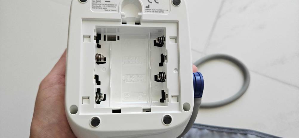 Blutdruckmessgeraet-Oberarm-Test: leeres Batteriefach eines Blutdruckmessgeräts im Fokus.
