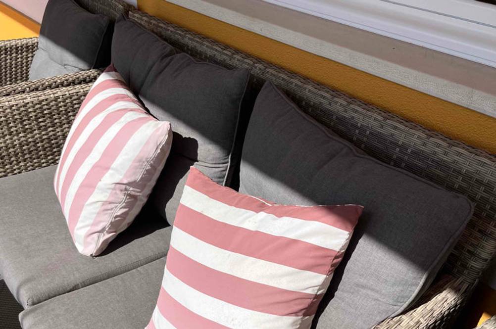 Rattansofa im Test: Rattansofa mit grauen Polstern und gestreifte Deokpolster darauf.