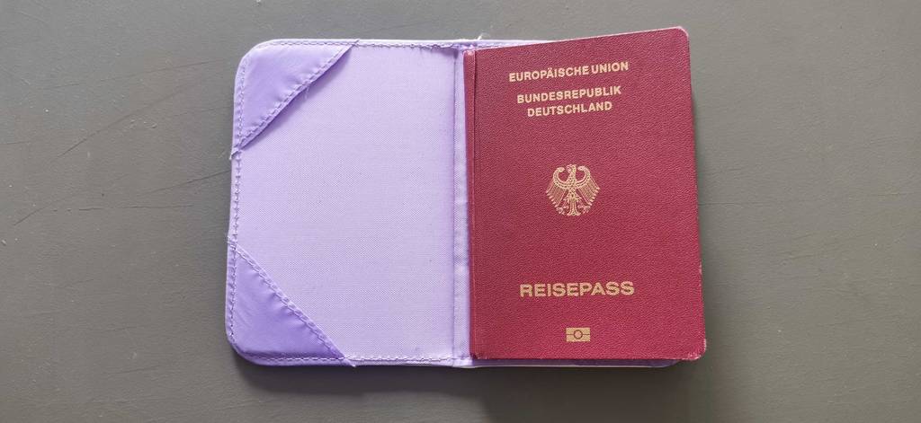 Reisepasshülle im Test: Auf einem weißen Tisch liegt ein deutscher Reisepass in lila Reisepasshülle.