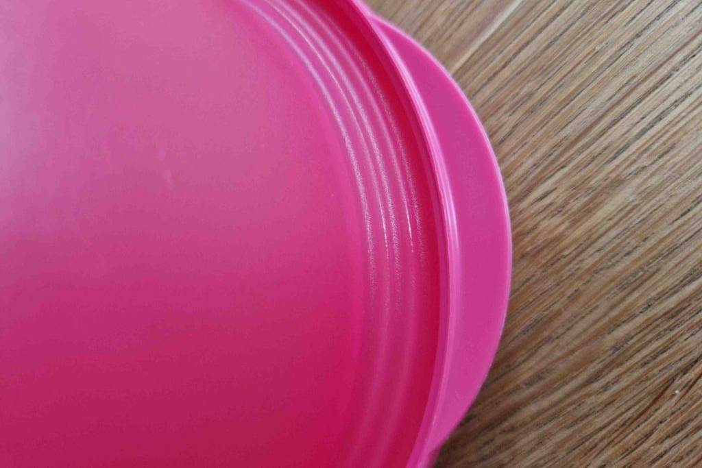 Tupperware im Test: Rosa Decker einer Schüssel in Nahaufnahme auf Holzoberfläche