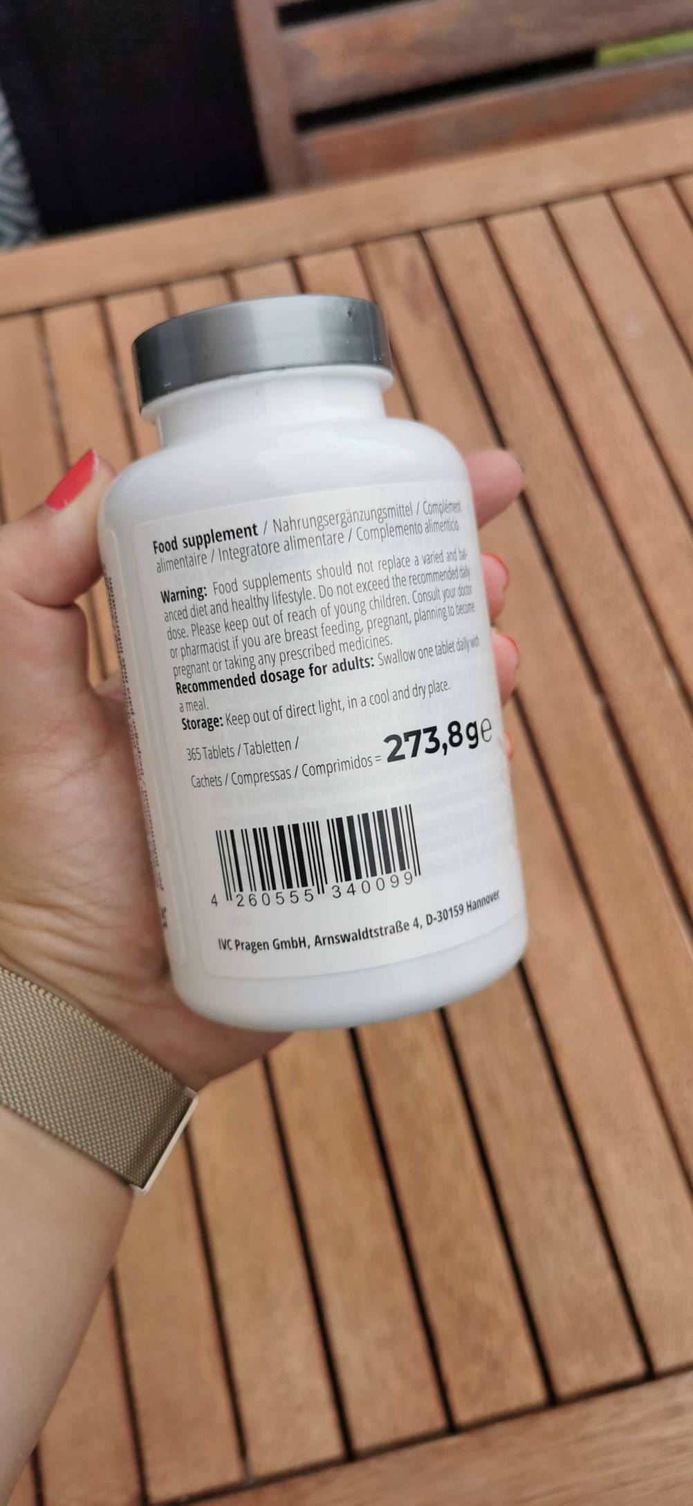 Im Test: Eine Hand hält eine Dose Zinktabletten mit der Rückseite nach vorne vor einen Holzhintergrund.