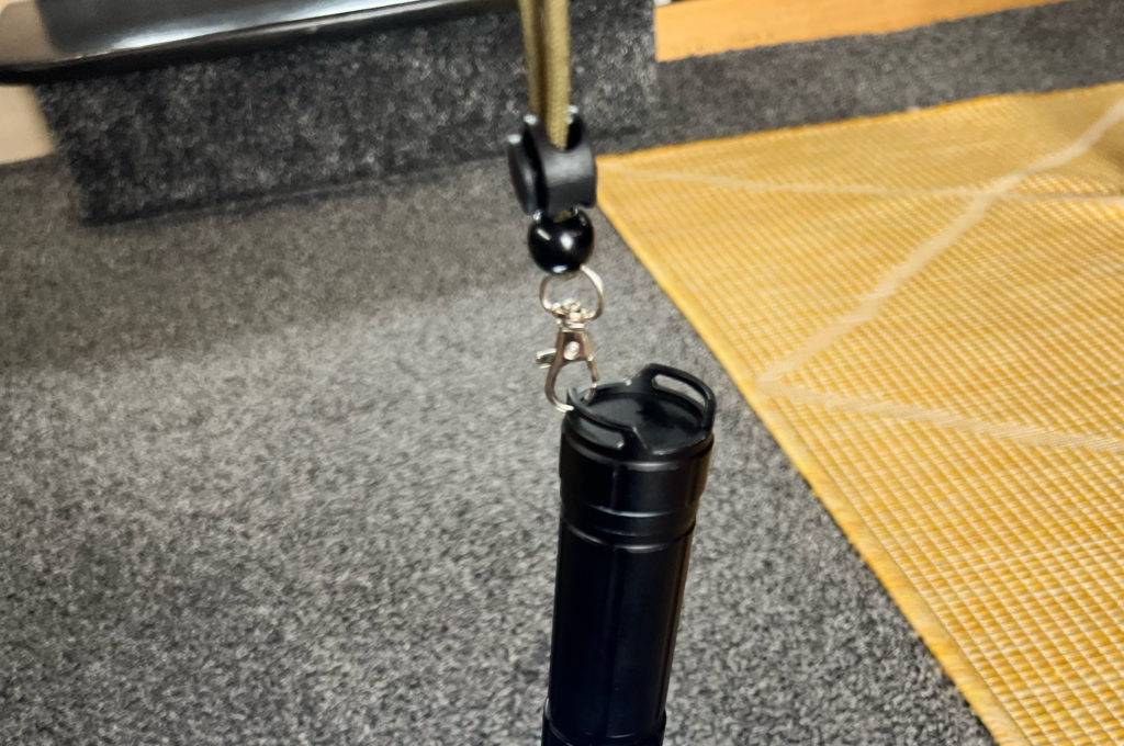 Eine getestete 10.000-Lumen-Taschenlampen hängt nach unten und bestrahlt einen grauen Teppich.