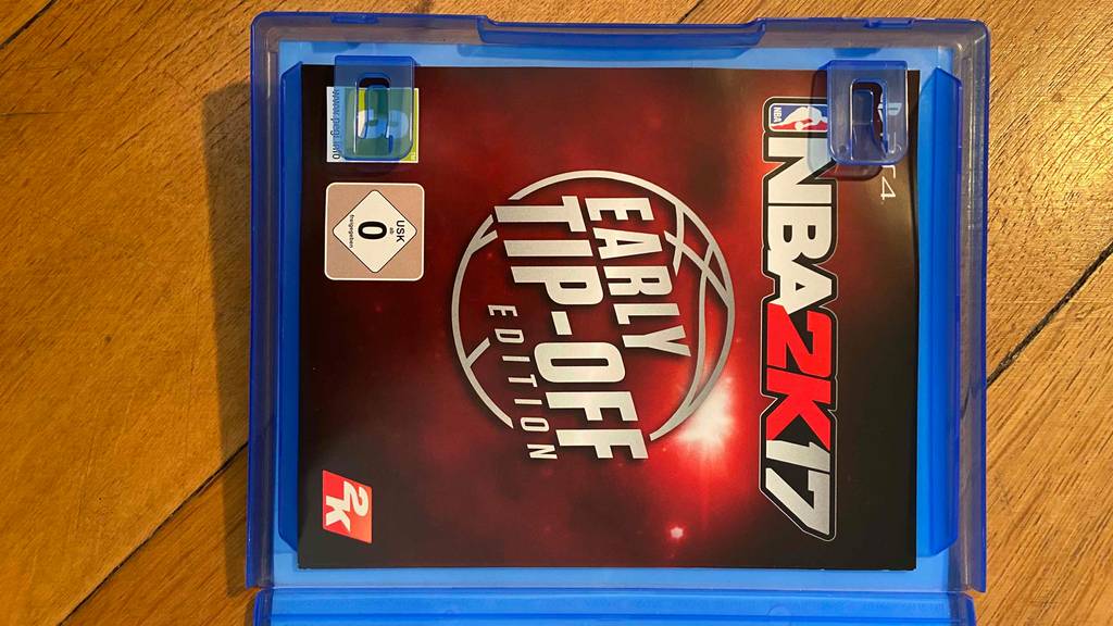 PS4-Spiele-Test: geöffnete Verpackung von INBA2K17-Spiel mit Broschüre darin.