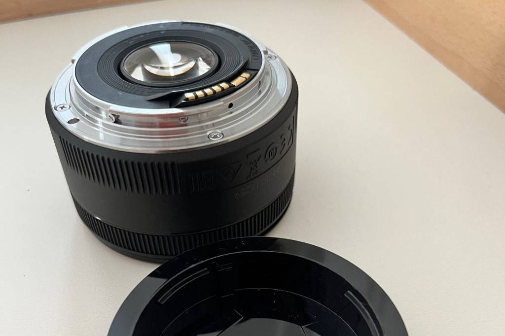 Objektive für Canon im Test: Objektiv mit abgeschaubtem Objektivdeckel davor auf heller Oberfläche