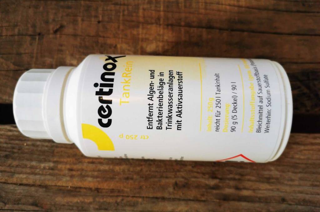 Im Test: Eine Flasche Frischwassertank-Reiniger liegt horizontal auf einer Holzfläche.