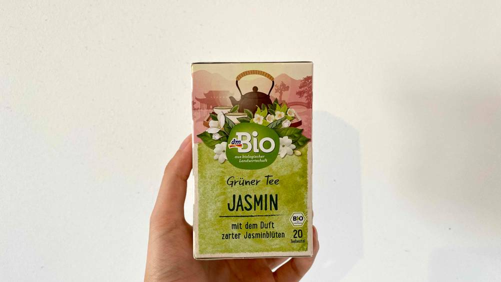 Jasmintee getestet: Eine Hand hält eine Packung vor einen hellen Hintergrund.
