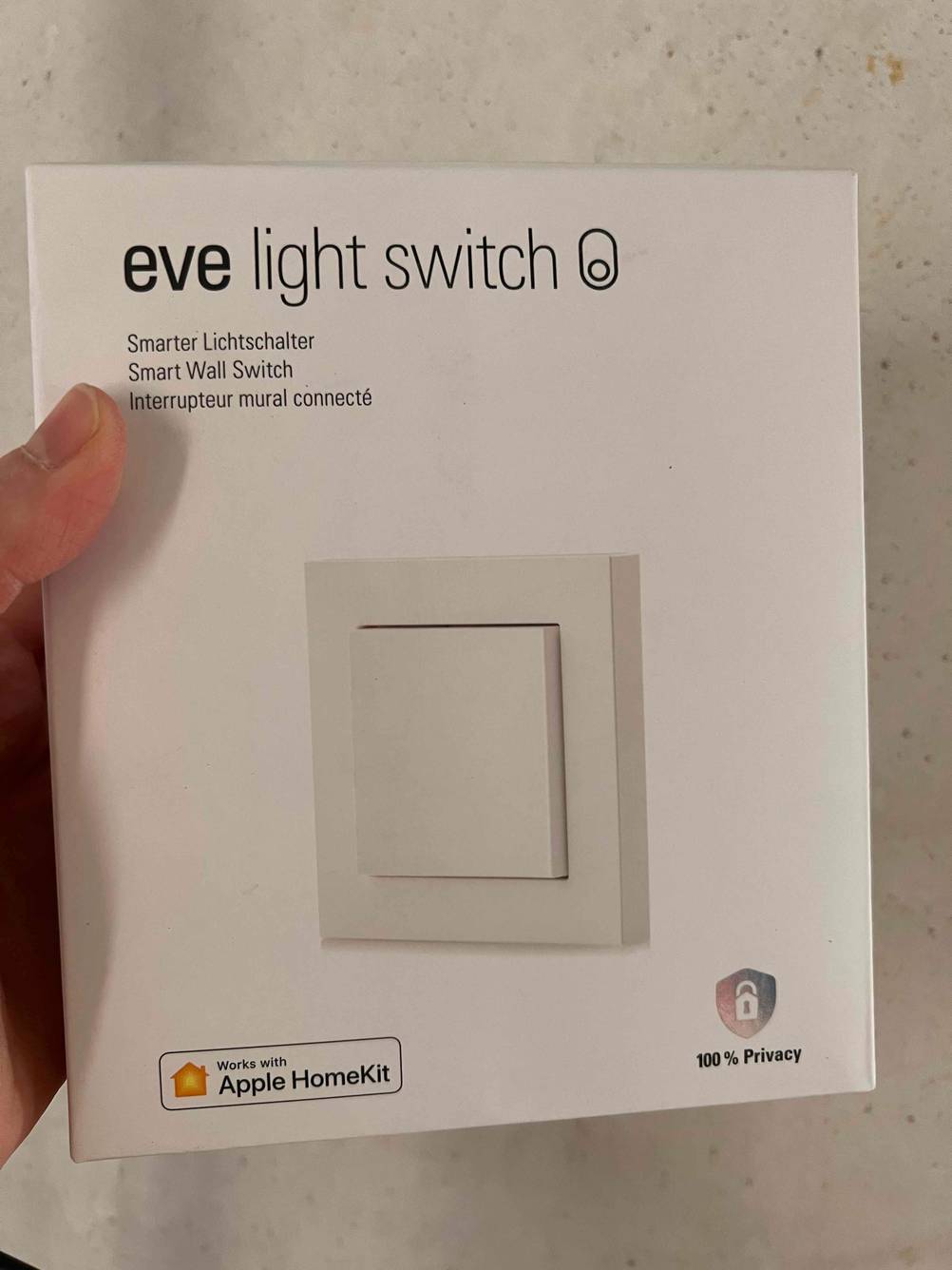 Smart-Home-Lichtschalter getestet: Eine Hand hält einen verpackten Smart-Home-Lichtschalter vor eine helle Wand.