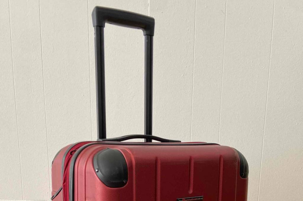 Ein großer roter Koffer steht zum Reisen bereit.