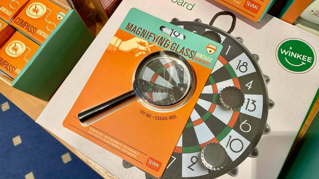 Eine getestete Lupe liegt auf der Verpackung einer Dartscheibe.