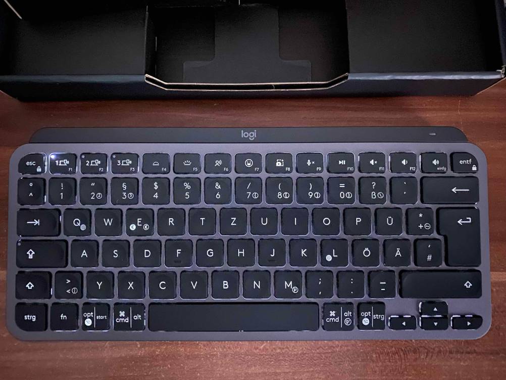 Eine getestete beleuchtete Tastatur steht vor einem Karton auf einer Holzfläche.