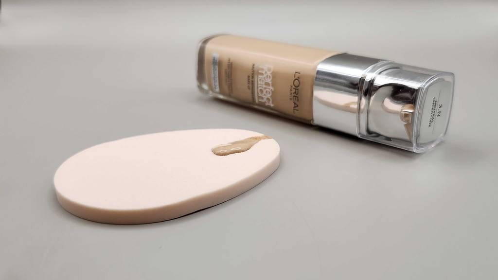 Die getestete L’Oréal-Foundation liegt hinter einem Pad, worauf sich Foundation befindet.