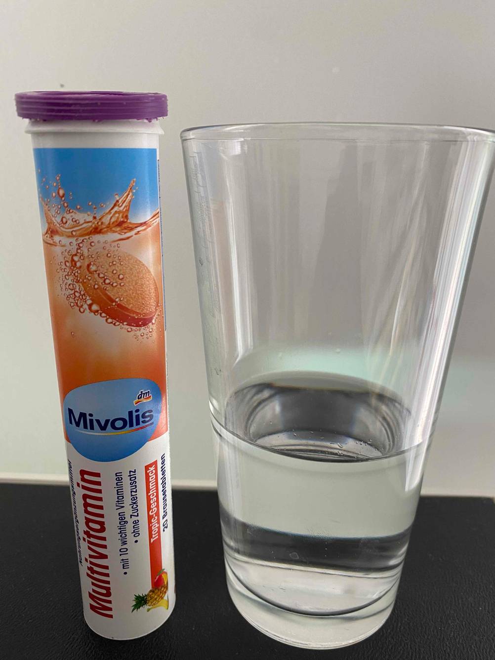 Multivitamin-Tabletten im Test: Eine Packung Multivitamin-Tabletten neben einem Glas auf dunkler Oberfläche
