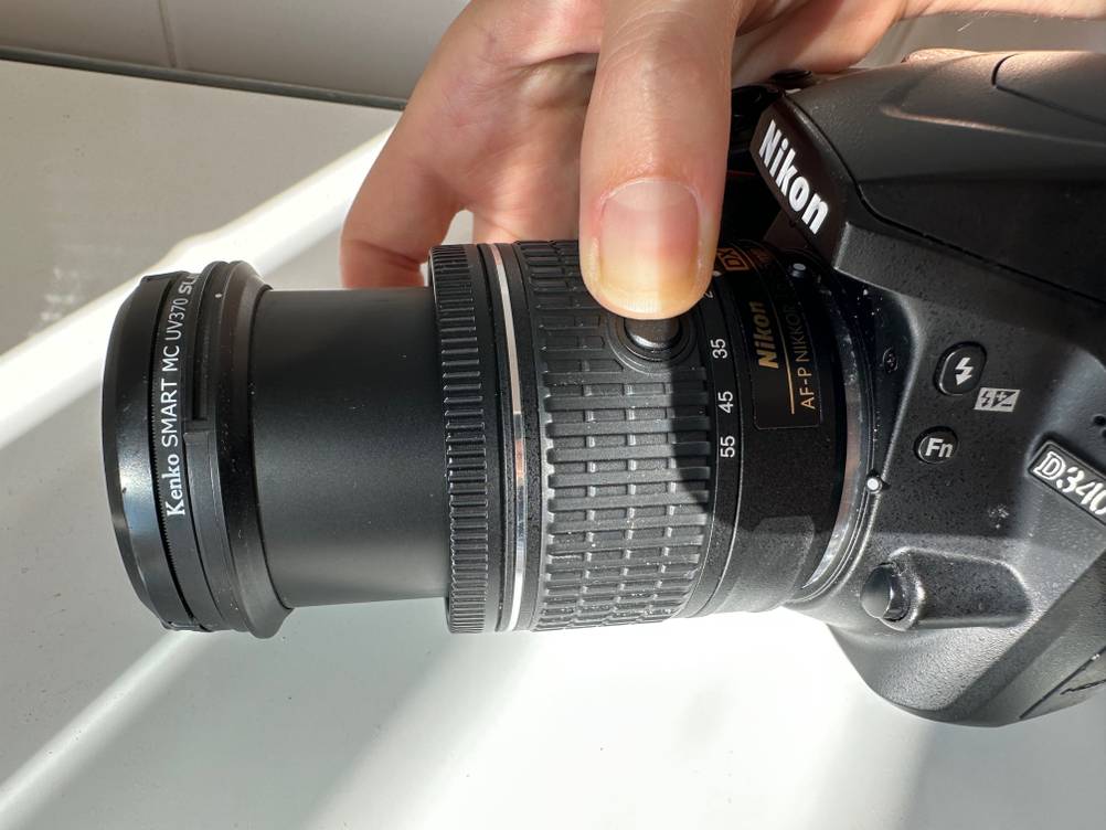 Objektiv für Nikon getestet: Eine Hand hält eine Kamera mit angeschlossenem Objektiv vor eine helle Fläche.