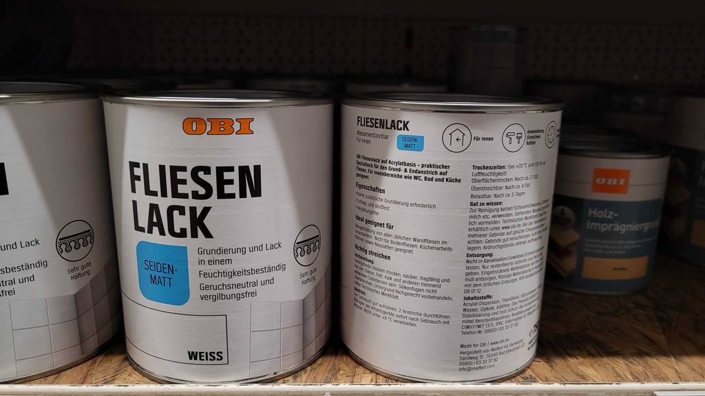 Test: Zwei Dosen Fliesenlack stehen in einem Regal, bei welchem eine Dose von vorn und die andere von der Rückseite aus ersichtlich ist.
