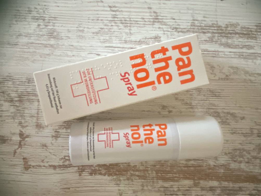 Die Verpackung und das getestete Panthenol in Sprayform liegen nebeneinander.