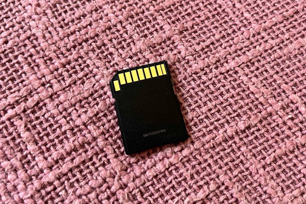 SD-Karte im Test: Eine Karte mit Rückseite nach oben auf einem rosa Stoff