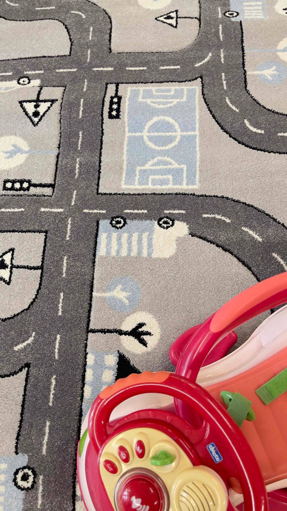 Ein hellgrauer getesteter Spielteppich mit Straßenzügen liegt ausgebreitet auf dem Boden.