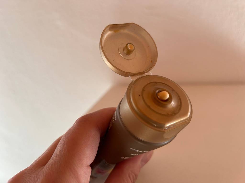 Getesteter Gesichtsbräuner in der Hand mit geöffnetem Decke.